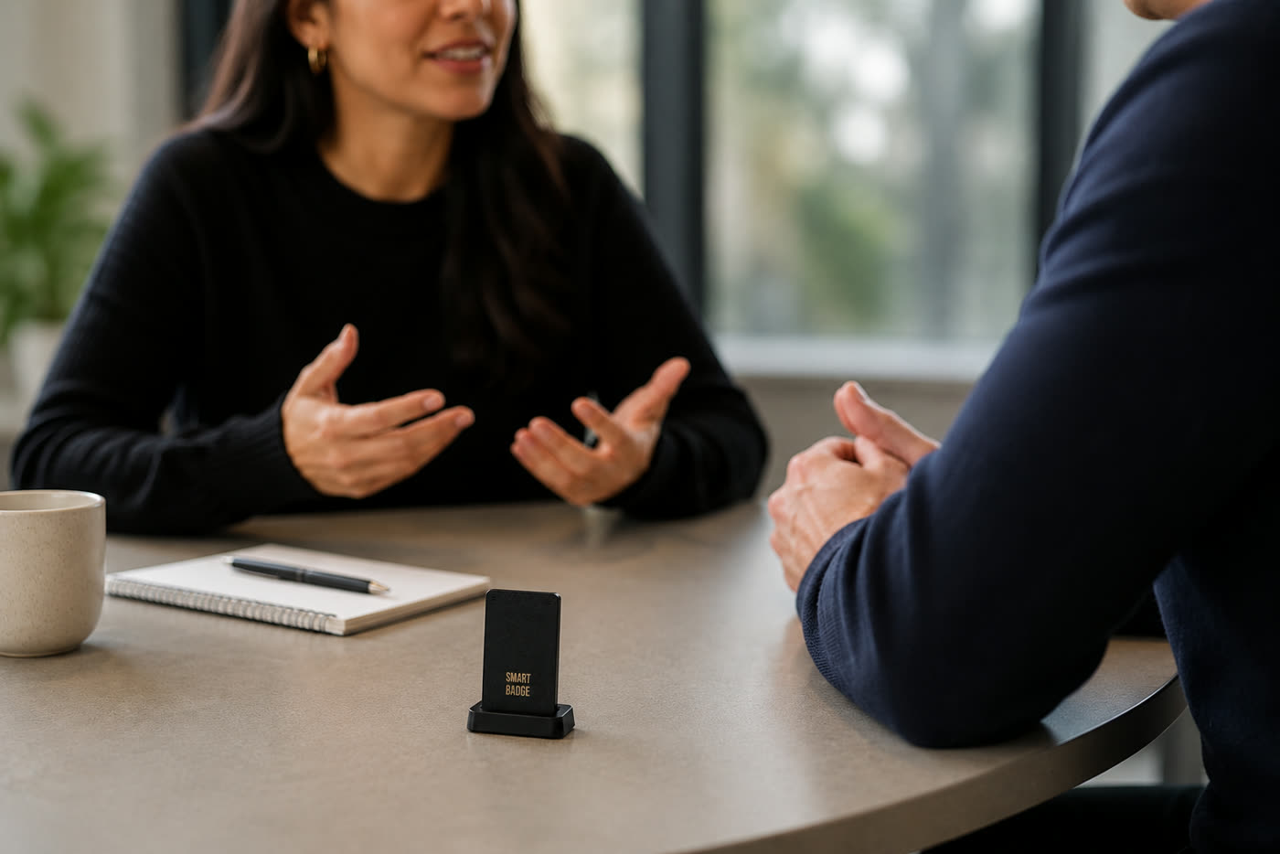 Reunião 1:1 com o Smart Badge sobre a mesa, capturando a conversa do mundo real